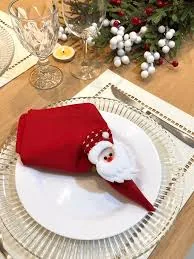 Aro de guardanapo con figura de Papa Noel y servilleta roja doblada sobre plato blanco